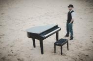 Josef Barnickel am Strand mit Klavier.